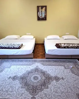 two beds sitting in a room with a rug at 5-BEDROOM FERRINGHI HOUSE with WIFI , NETFLIX , BBQ SET , 5 MINUTES WALK to BEACH in Batu Ferringhi