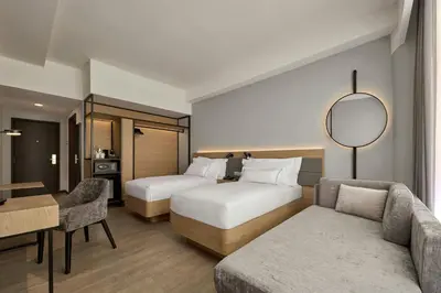 a hotel room with two beds and a couch at AC Hotel by Marriott Ipoh in Ipoh