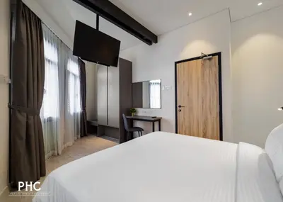a bedroom with a white bed and a wooden door at Macallum Central Hotel Managed by The Ascott Limited in George Town