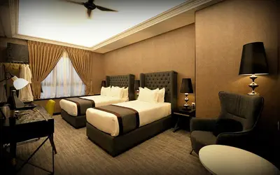 a hotel room with two beds and a chair at 1969 Business Suites Bandar Botani, Ipoh in Ipoh