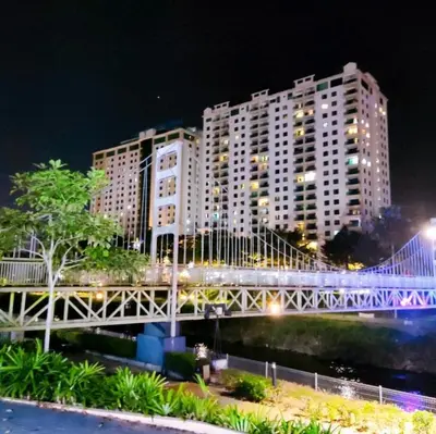a bridge over a river in front of a large building at K. Riverfront apartment in Ipoh