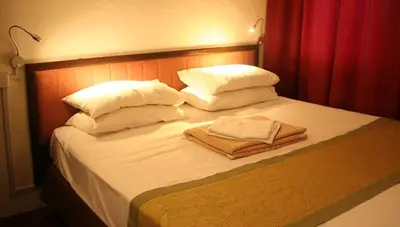 a bed with white pillows and towels on it at Red Inn Court in George Town