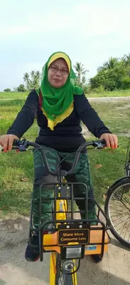 a woman is sitting on a bike at Homestay Damai Sri Kota in Kepala Batas