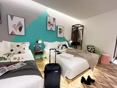 a bedroom with two beds and a suitcase on the floor at Apple 1 Hotel Queensbay in Bayan Lepas