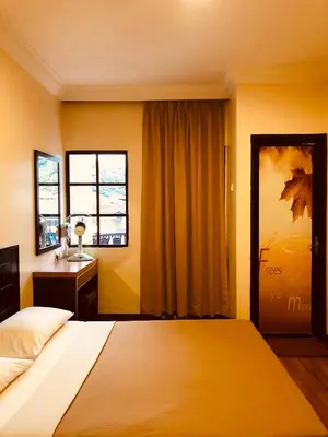 a bedroom with a bed and a desk and a window at Hotel Chua Gin in Cameron Highlands