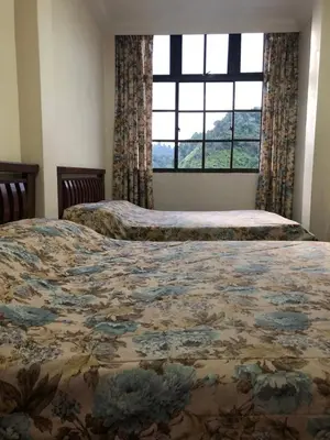 two beds in a bedroom with a large window at Hotel Chua Gin in Cameron Highlands