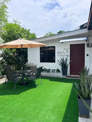 a patio with a table and chairs and an umbrella at Nadrah Cottage in Bayan Lepas