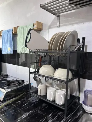 a shelf in a kitchen with plates and utensils at Nadrah Cottage in Bayan Lepas