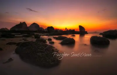a person standing on a beach at sunset at Sea & Wave #1 Coral Bay Apartment in Pangkor