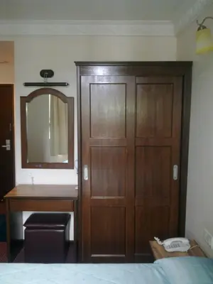 a bedroom with a wooden closet and a sink and a mirror at Hotel Remix in Cameron Highlands