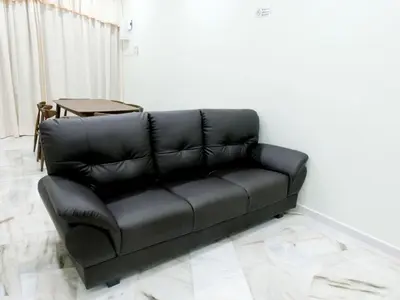 a black leather couch in a room with a table at Taiping Cozy Homestay II in Taiping