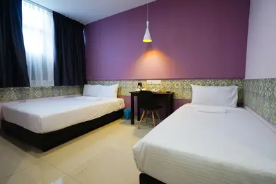 a hotel room with two beds and a table at Grand FC Hotel in George Town