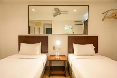 two beds in a room with a mirror on the wall at Tune Hotel Georgetown Penang in George Town