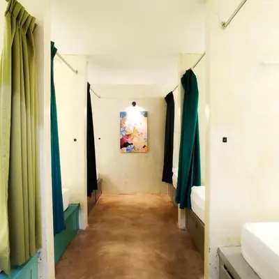 a hallway with green curtains and a painting on the wall at Beds In Garden Hostel in Ipoh