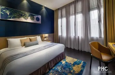 a hotel room with a large bed and a chair at Ropewalk Piazza Hotel Managed by The Ascott Limited in George Town