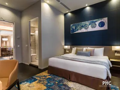 a bedroom with a large bed with a blue wall at Ropewalk Piazza Hotel Managed by The Ascott Limited in George Town