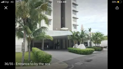a building with palm trees in front of it at By the sea Beach BABY in Batu Ferringhi
