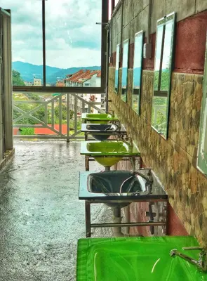 a row of green sinks in a public restroom at Kea Garden Mini Chalet in Cameron Highlands