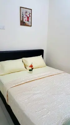 a bedroom with a bed with a white sheets and a picture at Ipoh EastEden Homestay in Ipoh