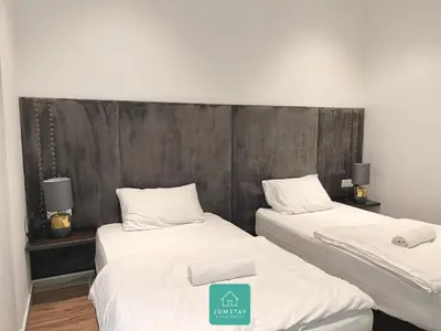 two beds in a room with a headboard at JOMSTAY Octagon Palm Suites Ipoh in Ipoh