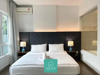 a bedroom with a bed and two lamps and a tub at JOMSTAY Octagon Palm Suites Ipoh in Ipoh