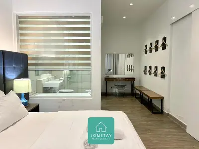 a bedroom with a bed and a bathroom with a sink at JOMSTAY Octagon Palm Suites Ipoh in Ipoh