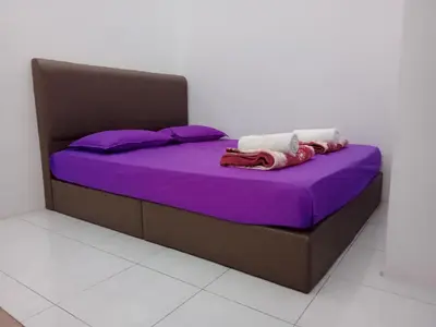 a bed with purple sheets and purple pillows at Wany Homestay & Guest House in Sungai Petani
