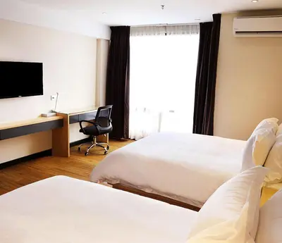 a hotel room with two beds and a desk with a computer at Rivertel in Teluk Intan