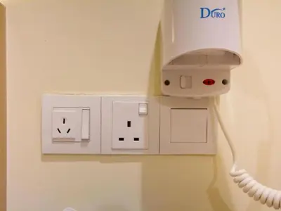 a white electrical outlet with a cord plugged into it at 118 Hotel Macalister in George Town