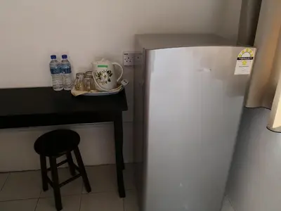 a refrigerator in a kitchen with a table and a stool at Fun Studio Pangkor in Pangkor