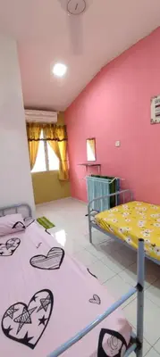 a room with two beds and a pink wall at Homestay D-Zara in Ipoh