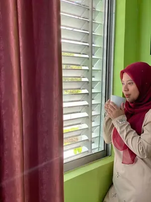 a woman holding a cup in front of a window at Ct Hotel in Sitiawan