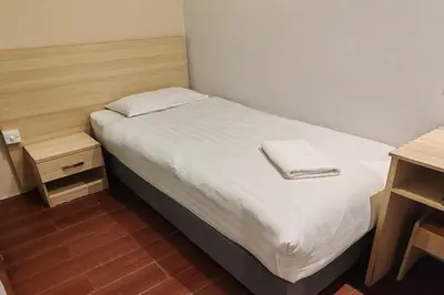 a small bedroom with a bed with white sheets and a table at Hotel 18 Ipoh Aeon Mall in Ipoh