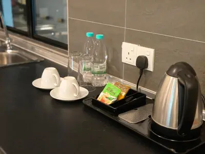 a kitchen counter with a coffee pot and plates and bottles of water at RPGC Garden Hotel in Ipoh