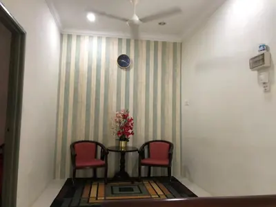 a room with two chairs and a table with flowers on it at Makmur homestay in Taiping