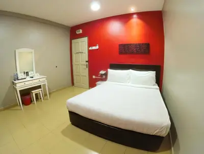 a bedroom with a large bed with a red wall at JV Hotel @ Bandar Tasek Mutiara in Simpang Ampat
