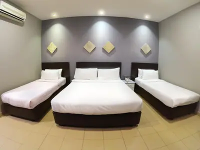 a hotel room with two beds with white sheets at JV Hotel @ Bandar Tasek Mutiara in Simpang Ampat