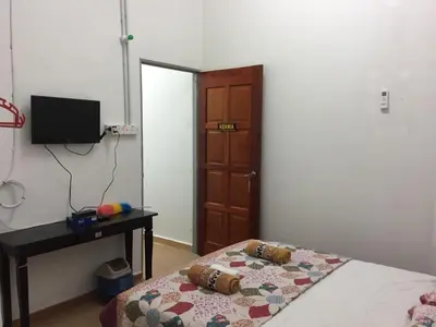 a bedroom with a bed and a desk and a door at Bunga Raya Guest House BALING in Baling