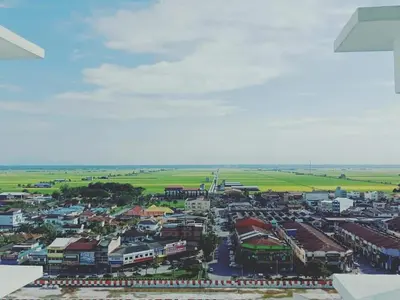 an aerial view of a town with buildings and a field at WindMill SunRise PaddyView Homestay in Sekincan