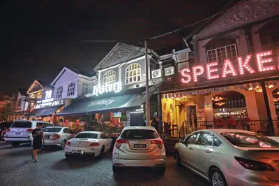 a street with cars parked in front of buildings at night at The Brownstone Hostel & Space in Ipoh