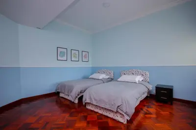 two beds in a room with blue walls and wooden floors at Fun Apartment @ Equatorial Hill Resort in Cameron Highlands