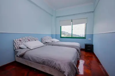 two beds in a room with blue walls and a window at Fun Apartment @ Equatorial Hill Resort in Cameron Highlands