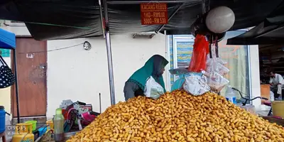a woman is standing behind a pile of food in a market at Rumah Tamu Azizah in Kampong Tanjong Bayan