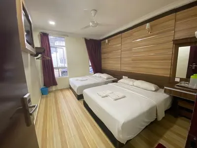 a hotel room with two beds and a mirror at Haji Saudi Hotel in Cameron Highlands