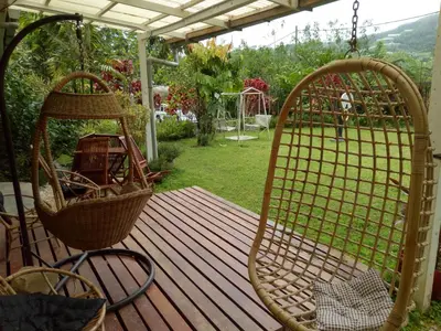 a porch with two swinging chairs on a wooden deck at Moonriver Lodge in Cameron Highlands
