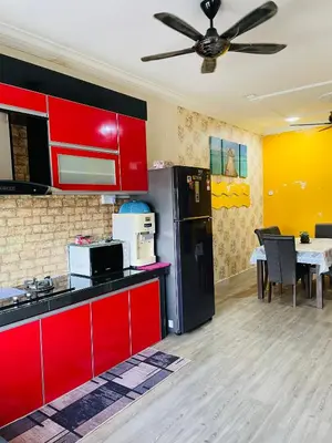 a kitchen with red cabinets and a black refrigerator at D Corner Islam Homestay in Kuala Kangsar