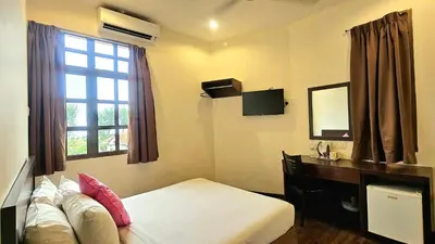 a bedroom with a bed and a desk and a window at Hotel 22 Gurney, Penang in George Town