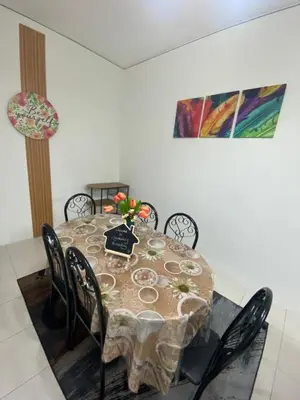a dining room table with chairs and a vase of flowers on it at SYA HONEY HOMESTAY with NETFLIX in Cameron Highlands