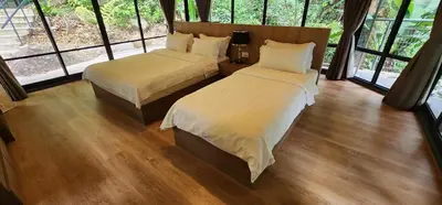 two beds in a room with large windows at Boulder Valley in Batu Ferringhi