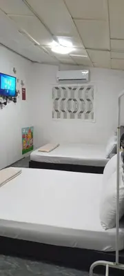 a white bed in a room with a tv at JSW Inn in Gelugor